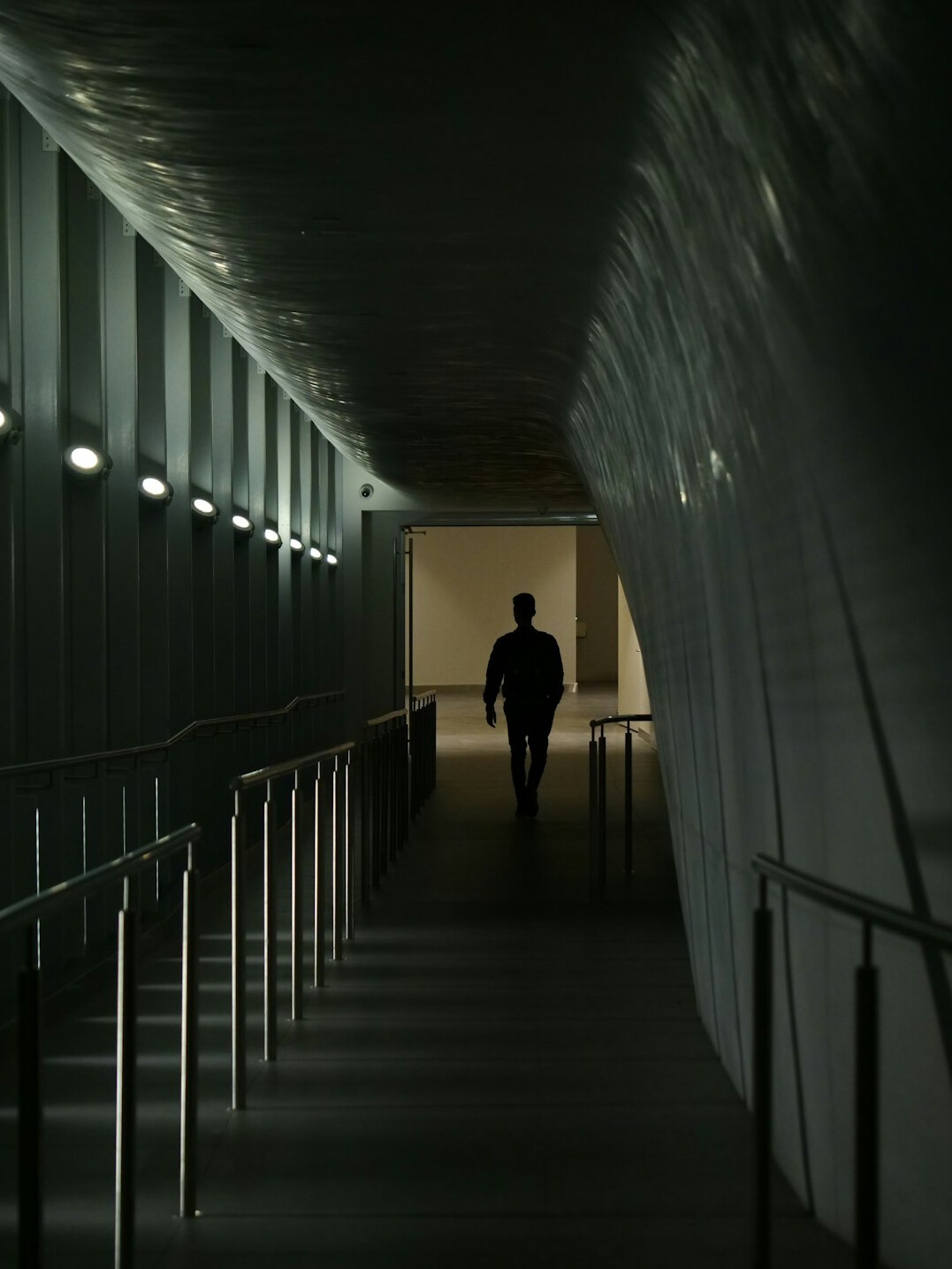 Distant silhouette of a person walking alone through a quiet urban passage